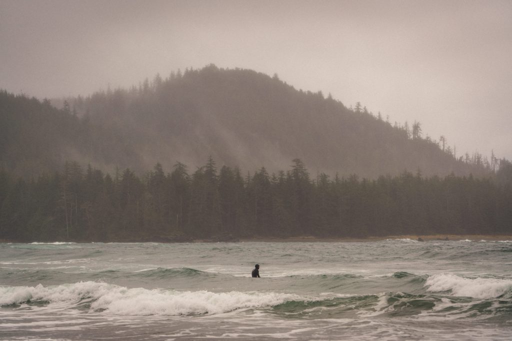 A photo of a surfer sitting on a surfboard in small waves