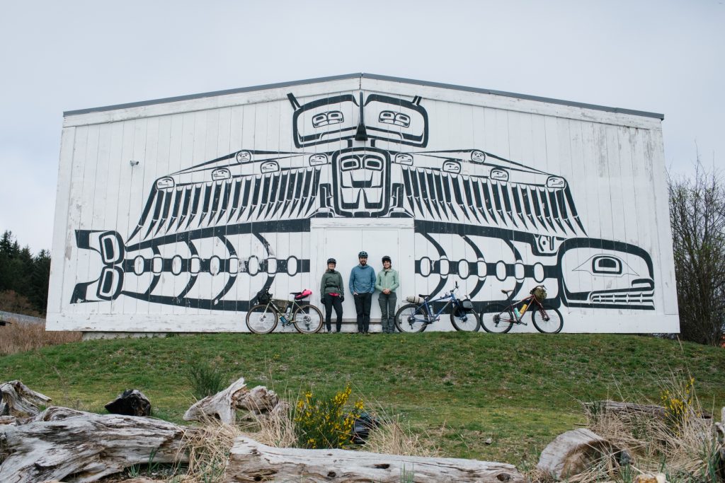 Three people standing infront of a big house on Cormorant Island
