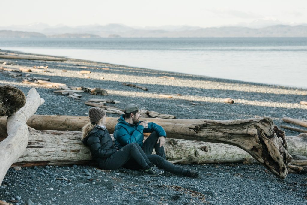 Two people sitting on a beach looking out to the ocean